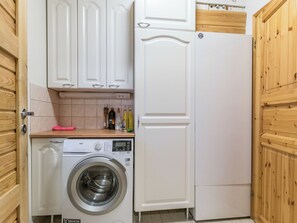 Une cuisine compacte équipée d’un lave-linge, d’un réfrigérateur blanc, de meubles en bois et d’un crédence carrelée.