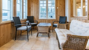 A cozy room with wooden walls and large windows, featuring a sofa, two chairs, and a small table. - Villa lahti by Interhome (Leppävirta)