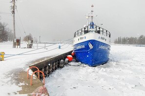 Een blauw schip genaamd 'LAUREN' afgemeerd aan een steiger, er ligt sneeuw op de grond.