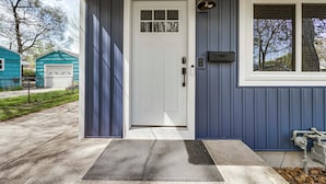 Ett hus med en vit ytterdörr, en liten veranda och en brevlåda.