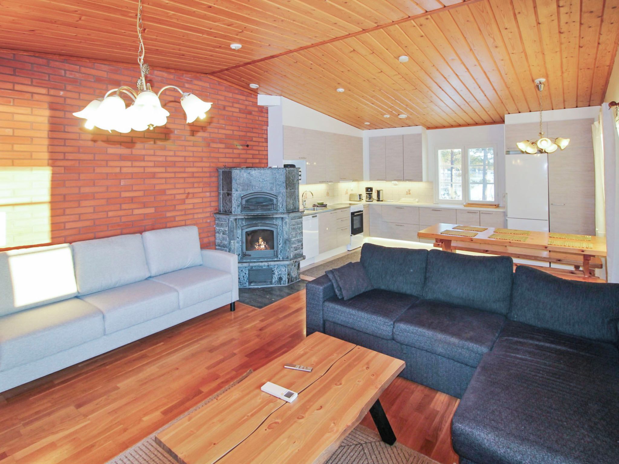 Un salon moderne avec une cheminée, un canapé, une table basse et un coin repas avec une table en bois.
