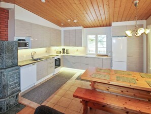 Moderni keittiö, jossa on puinen katto, sisäänrakennettu uuni, mikroaaltouuni ja jääkaappi.