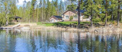 Una propiedad frente al lago con una casa, muelle y bosque circundante.