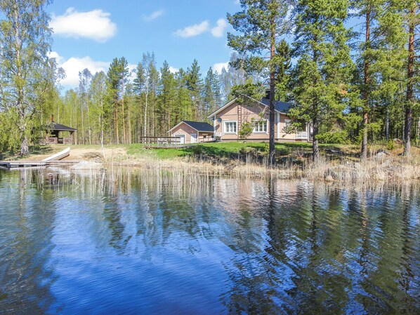 Una propiedad frente al lago con una casa, muelle y bosque circundante.
