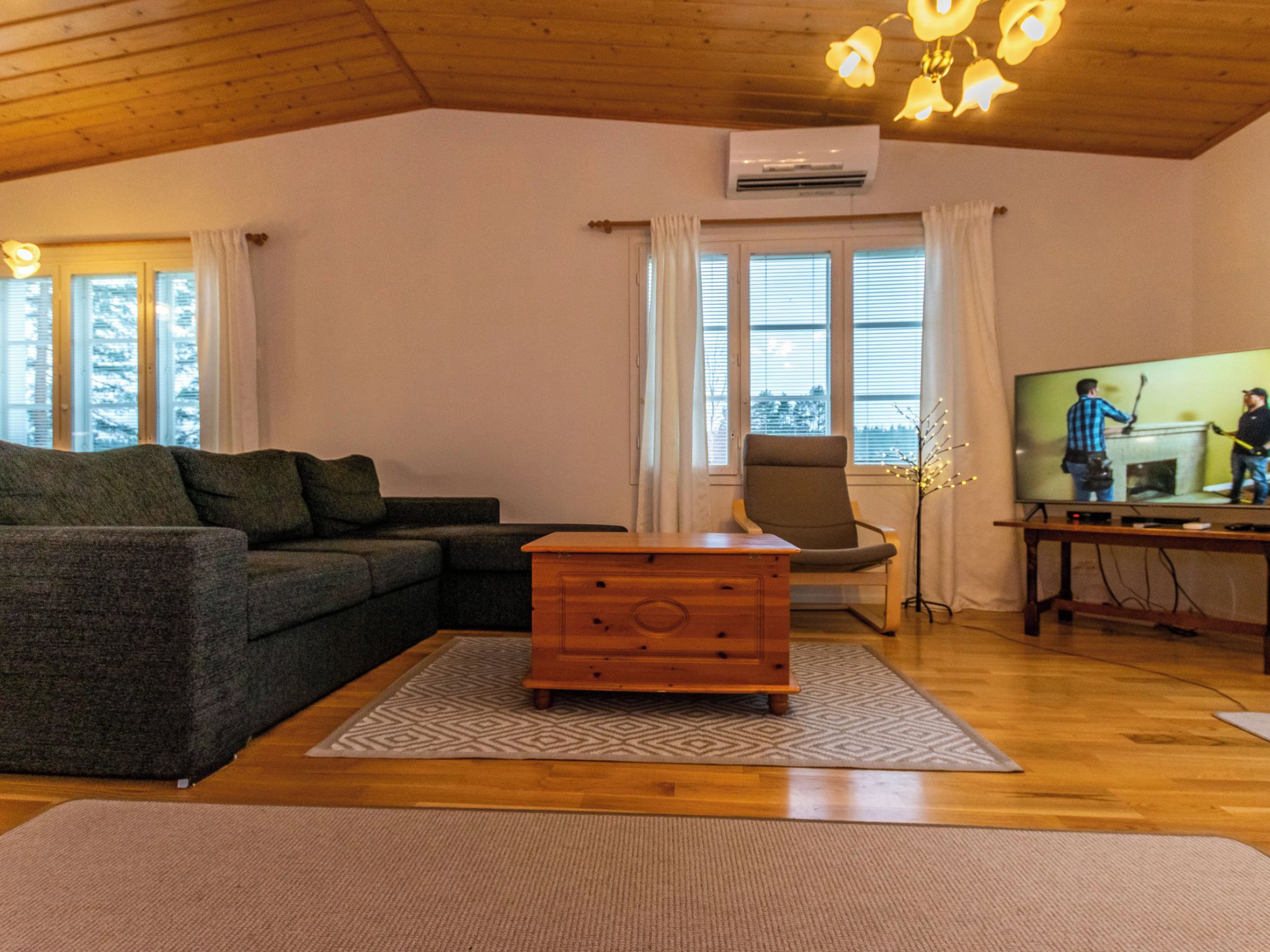 Een knusse woonkamer met een bank, een houten dressoir en een televisietoestel.