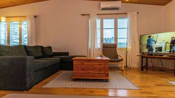Een knusse woonkamer met een bank, een houten dressoir en een televisietoestel.