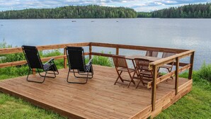 Een houten terras met buitenmeubilair met uitzicht op een meer.