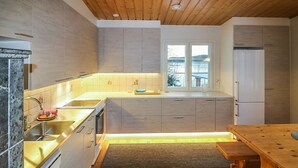 Een moderne keuken met houten kastjes, een roestvrijstalen spoelbak en een houten eettafel.