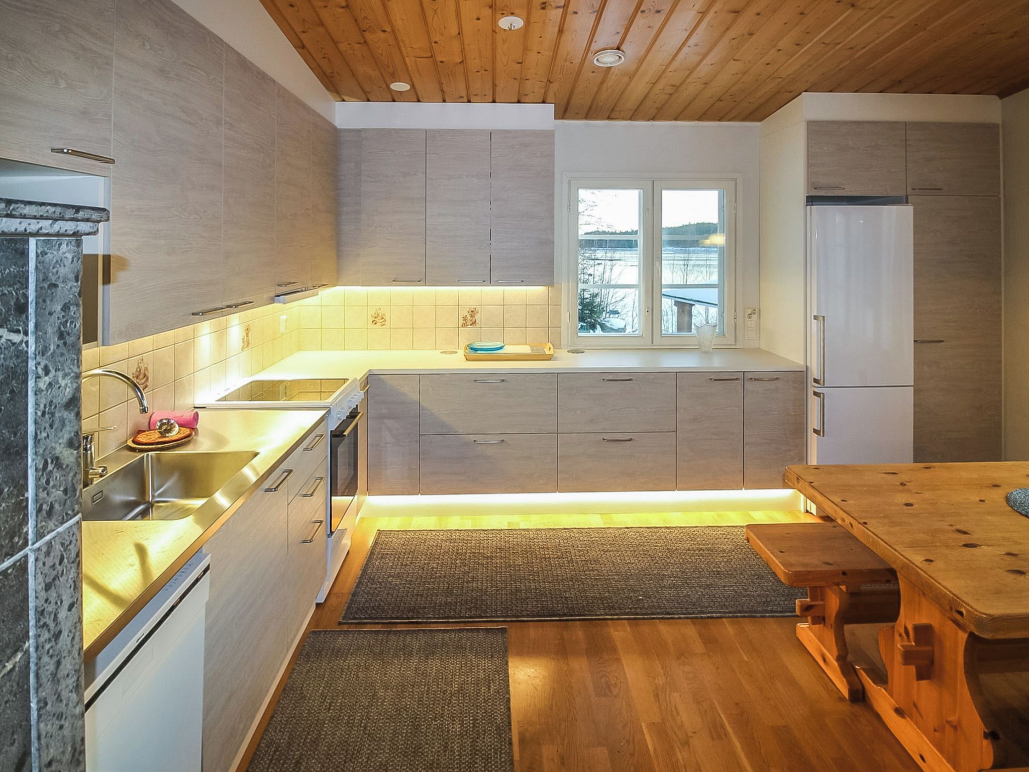 A modern kitchen with wooden cabinets, a stainless steel sink, and a window providing a view of the outdoors.