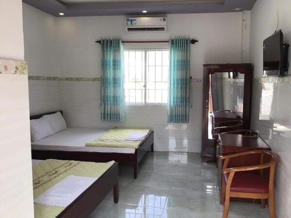 A hotel room with two beds, a desk, a chair, a TV, and a window with curtains.