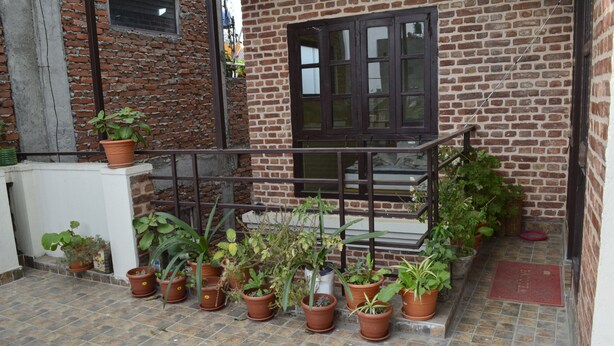 Um edifício de tijolos com varanda e vários vasos de plantas.