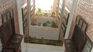 Um átrio amplo em vários níveis, com paredes de tijolo, várias janelas e plantas em vasos.