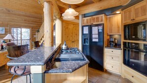A log cabin kitchen with a central island, wooden cabinets, and modern appliances. - 9 Mi to Slopes! Hot Tub Hideaway in Breckenridge (Breckenridge)
