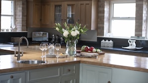 A kitchen with a wooden countertop, a sink, and cabinets. There is a vase with flowers on the counter. - Hill Top Farm, Askrigg, Yorkshire Dales (Askrigg, Nr Leyburn)