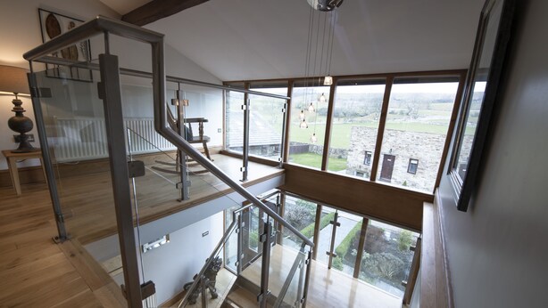 A spacious interior with a high ceiling, a staircase leading to an upper level, and large windows offering a view of the outdoors. - Hill Top Farm, Askrigg, Yorkshire Dales (Askrigg, Nr Leyburn)