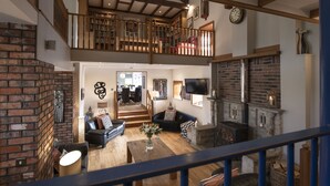A spacious living area with a fireplace, a staircase to an upper level, and a cozy seating arrangement. - Hill Top Farm, Askrigg, Yorkshire Dales (Askrigg, Nr Leyburn)