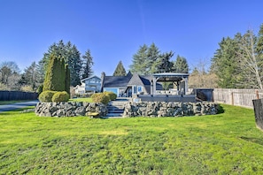 Ein zweigeschossiges Haus mit Natursteinfundament, einer Veranda und einem gepflegten Rasen.