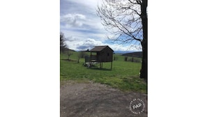 A rustic wooden structure in a grassy field with a clear sky.