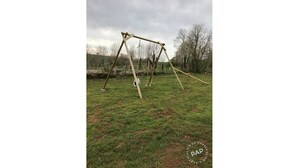 A swing set in a grassy field with a cloudy sky.