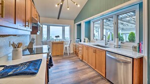 Una cocina moderna con armarios de madera, lavavajillas de acero inoxidable y un amplio ventanal que proporciona luz natural.