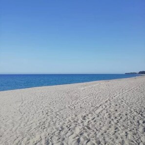 Ein weiter Sandstrand mit Fußspuren, die zum Wasser führen.