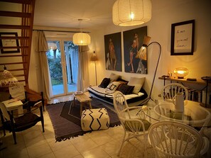 Ein gemütliches Wohnzimmer mit einer Couch, Sesseln, einem Couchtisch und Kunstwerken an den Wänden.