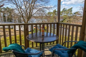 A wooden deck with a round table and two chairs, overlooking a lake and trees. - Lagoon 2 - Mobile homes Lagoon (Lychen)