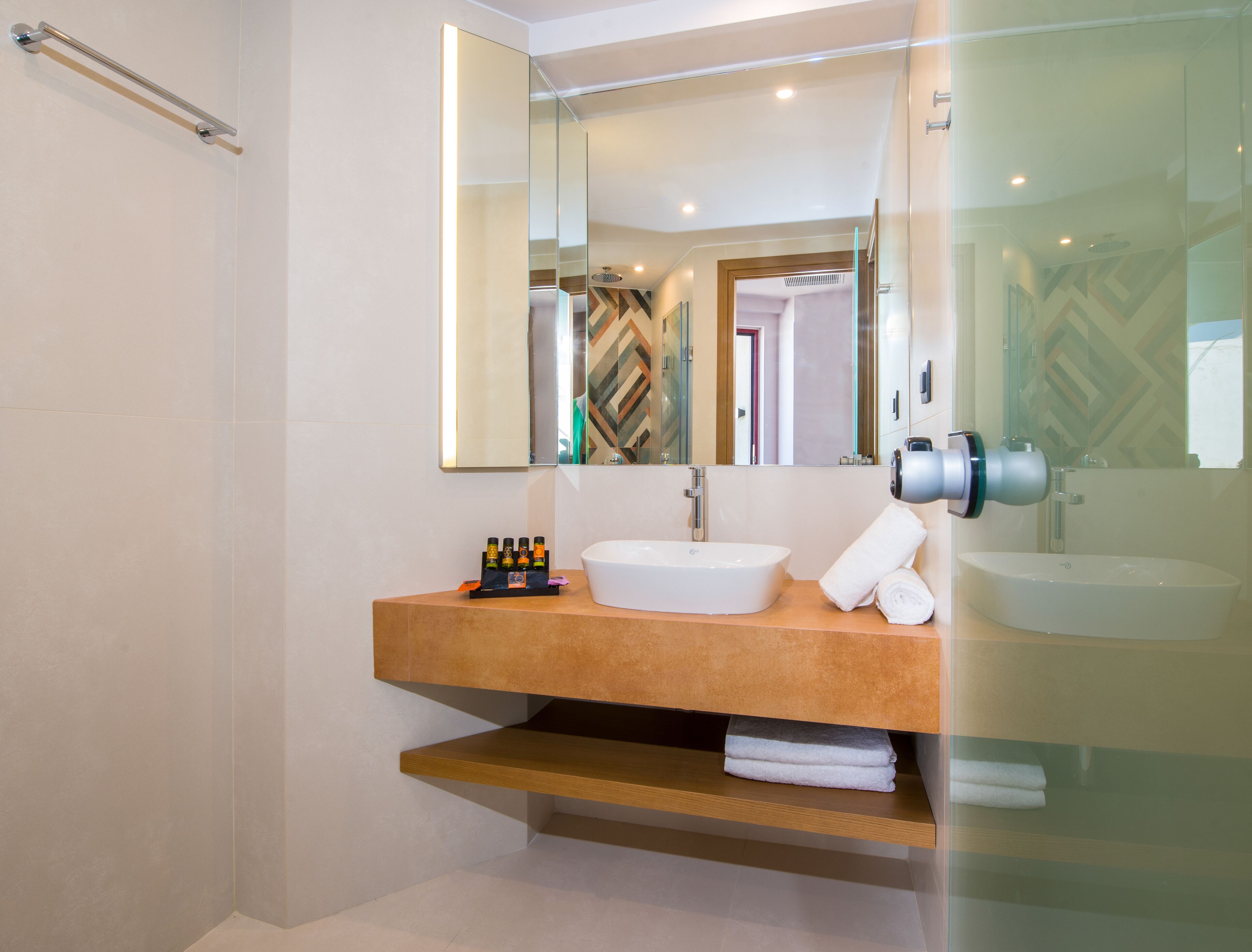 A modern bathroom with a large mirror, a sink, and a towel rack.