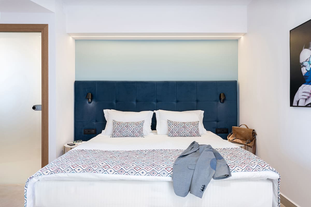 A neatly made bed with a patterned bedspread, a blue headboard, and a single pillow.