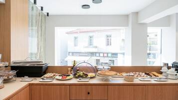 Un bufé de desayuno con diversas opciones de comida y vista a un edificio con señalización.