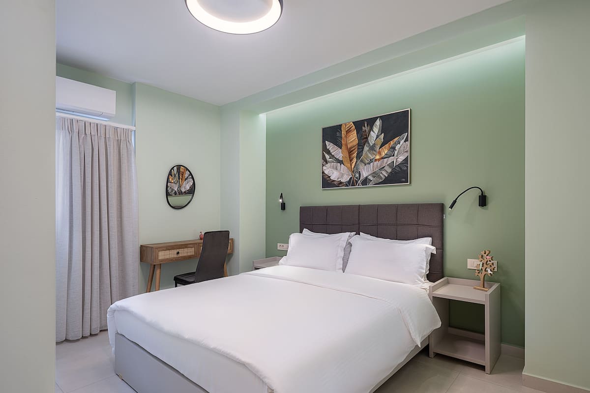 A bedroom with a large bed, a desk, a chair, and a nightstand.