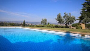 Una piscina azul cristalina con vistas a colinas y árboles distantes.