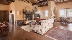 Un salón amplio con chimenea, vigas de madera y una pared de piedra.