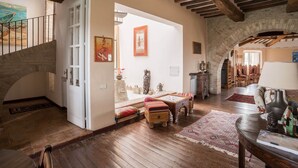 Amplia sala de estar con piso de madera, una escalera y un arco de piedra.