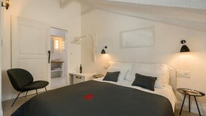 Un dormitorio con una cama, una silla, una mesita de noche y una pequeña mesa.