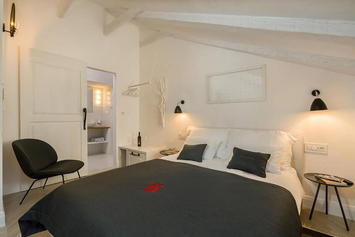 Un dormitorio con una cama, una silla, una mesita de noche y una pequeña mesa.