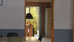 Un espace repas comprenant une table et des chaises, une lampe, et donnant sur un paysage verdoyant.