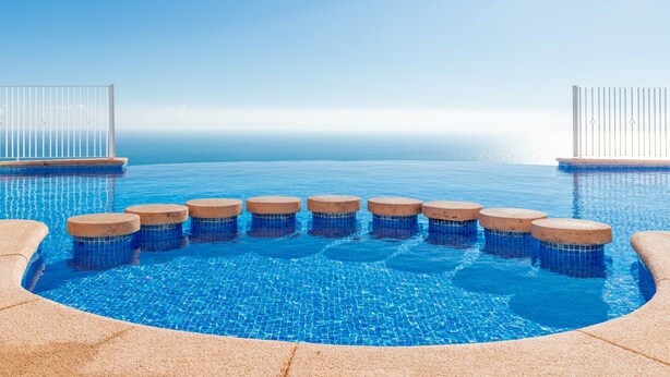 Ein Infinity-Pool mit freiem Blick auf den Horizont, umgeben von Steinstufen und Geländern.