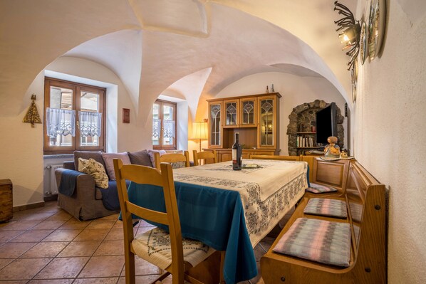 Un coin repas avec une table dressée pour quatre personnes, un buffet en bois et une cheminée en pierre.