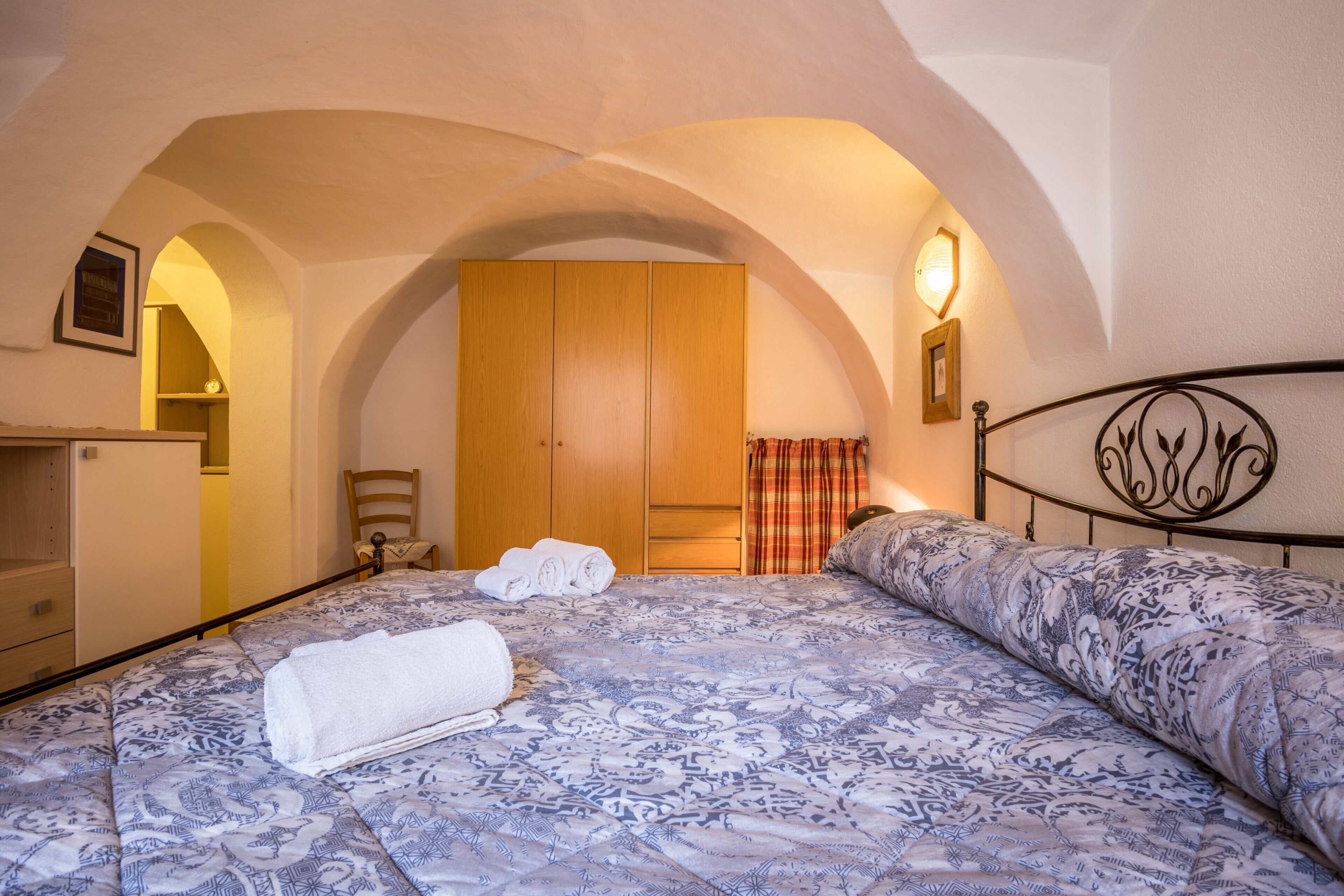 A bedroom with a bed, a wardrobe, a chair, and a small table.