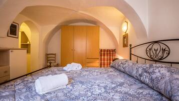 A bedroom with a bed, a wardrobe, a chair, and a small table.