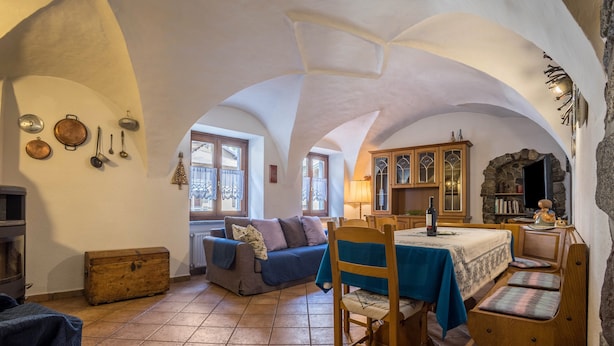 Un interior rústico con comedor, sofá y chimenea de piedra.