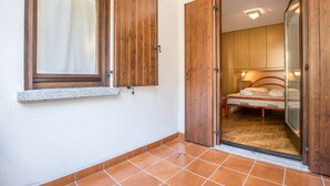 A bedroom with a wooden door, a bed, and a window with a curtain. - Apartment "Bellavista" with Lake Views & Terrace (Mezzolago)