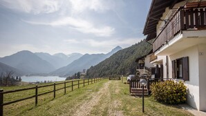 A building with a balcony, a paved path, and a view of mountains and a lake. - Apartment "Bellavista" with Lake Views & Terrace (Mezzolago)