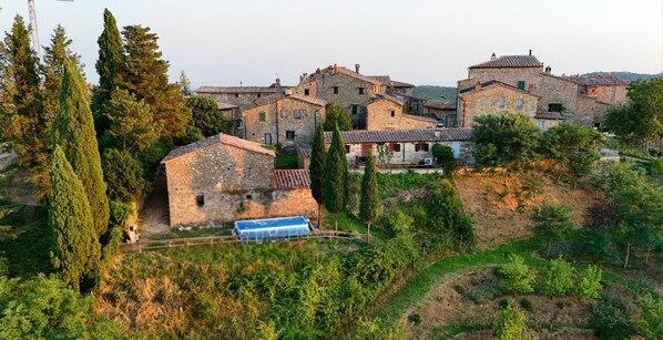 A village with stone buildings, a clear sky, and a blue car parked in front.
