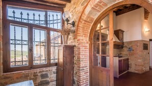 Une cuisine rustique avec des murs en briques apparentes, des armoires en bois et une grande fenêtre ornée de barreaux en métal.
