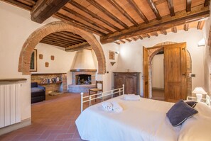 A bedroom with a large bed, a fireplace, and an arched doorway.