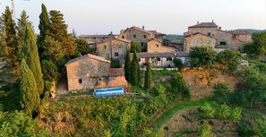 A village with stone buildings, a clear sky, and a blue car parked in front.
