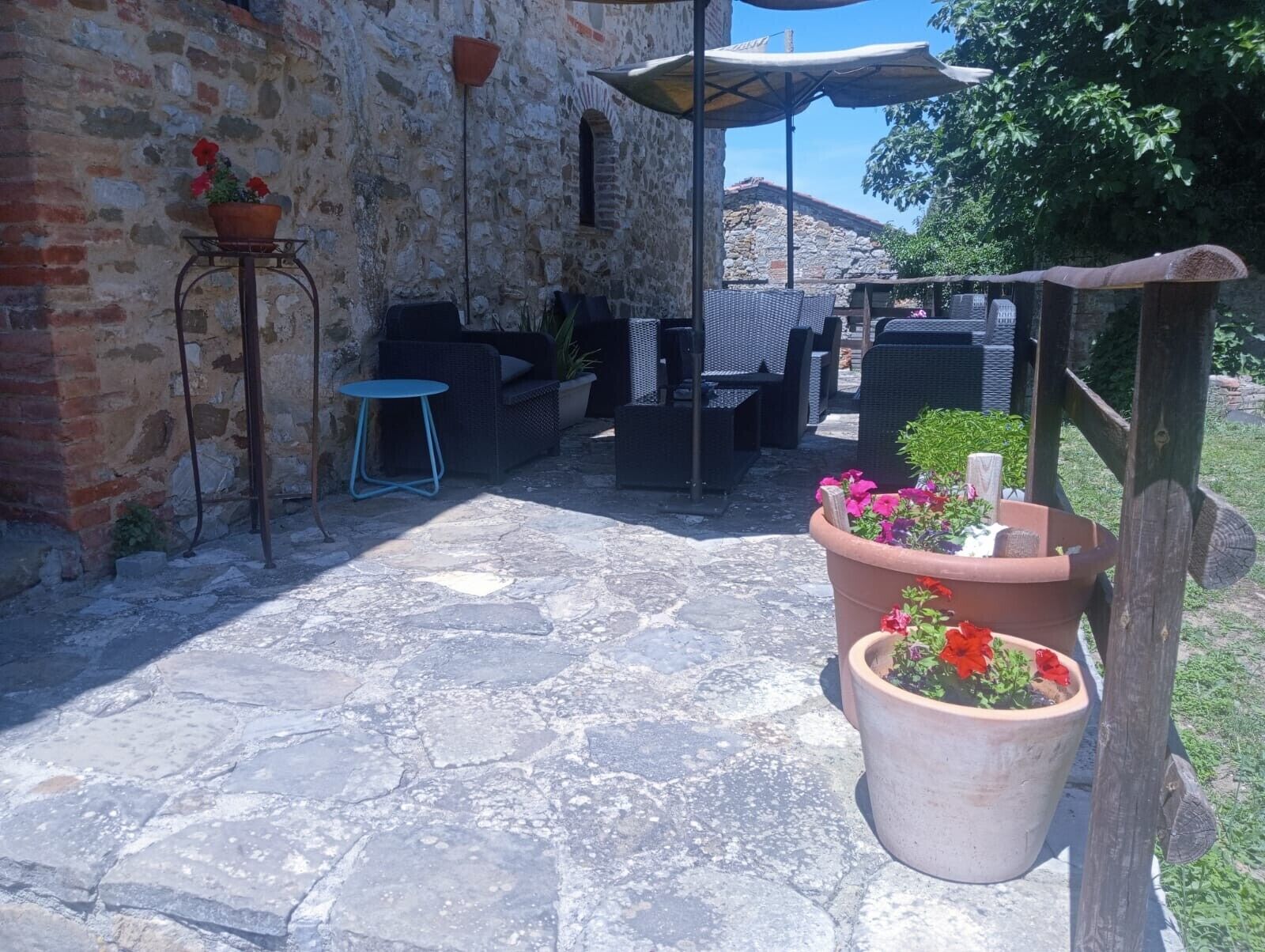 An outdoor patio area with stone flooring, wicker furniture, and potted plants.