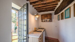 A compact kitchen with a wooden ceiling, a sink, and a small countertop. - Casale Rosennano Apartment – Shared Garden, Wi-Fi, Medieval Setting (Rosennano)